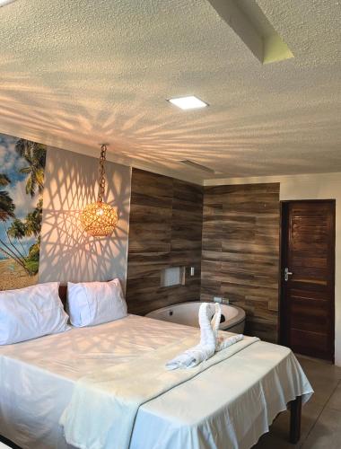 a bedroom with a bed and a bath tub at Suítes Ventos e Velas Praia in Pôrto de Pedras