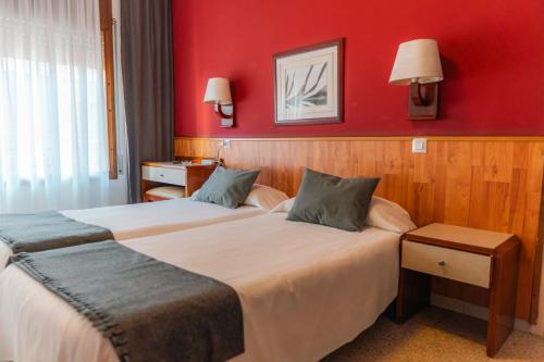 two beds in a hotel room with red walls at Hostal Regina in Blanes