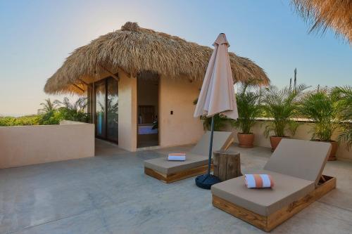 a patio with an umbrella and chairs and a house at Casa Cambria in Puerto Escondido