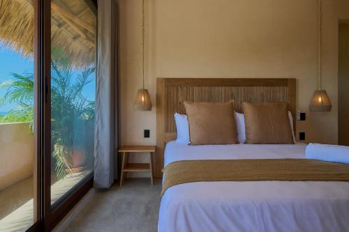 a bedroom with a bed and a large window at Casa Cambria in Puerto Escondido