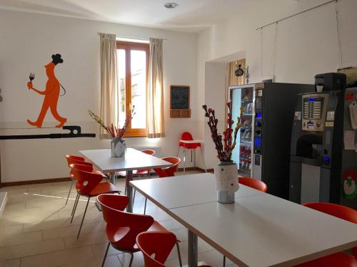 a kitchen with white tables and red chairs at L'Archetto in Cremona