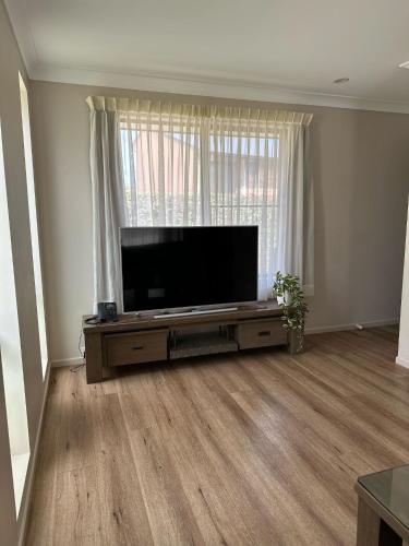 a living room with a large flat screen tv at Quality Hotel City Centre in Coffs Harbour