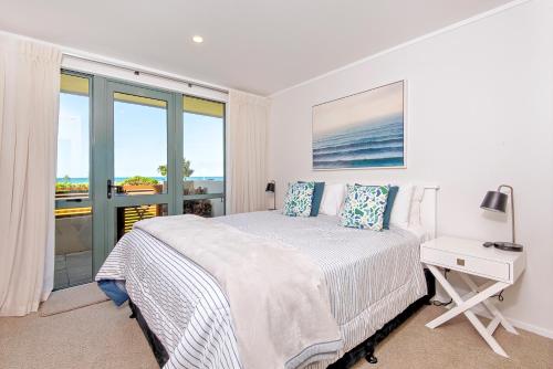 a bedroom with a bed and a desk with a window at Beachpoint Apartments in Ohope Beach
