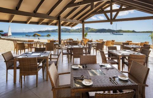 a restaurant with tables and chairs on the beach at Plantation Island Resort in Malolo Lailai
