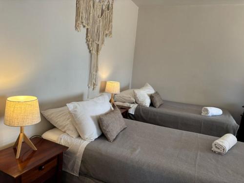 a room with two beds and a table with two lamps at Cabañas Caleta Hueso in Taltal
