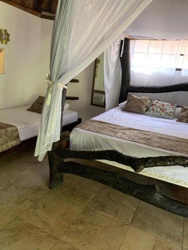 a bedroom with two beds and a canopy at Hostal Villa Cata in El Zaino