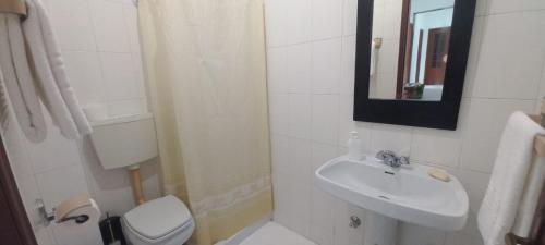 Un baño con lavabo, inodoro y espejo. en Golden House, en Fátima