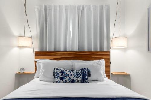 a bed with two lamps and a pillow on it at Swell House Santa Cruz in Santa Cruz