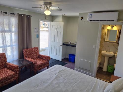 a bedroom with a bed and two chairs and a sink at Manor Motel in Southampton