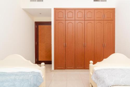 a bedroom with two beds and a wooden closet at sand and beach haven at Ajman Corniche! in Dubai