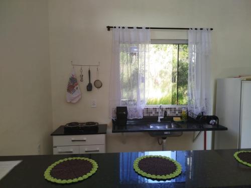 a kitchen with a table and a sink and a refrigerator at Chalé do Ypê in Pirenópolis