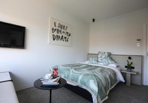 a bedroom with a bed and a table and a tv at Barrys Beach Road Hotel in Sydney