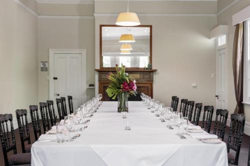 a long table with glasses and flowers in a room at Peppers Manor House in Sutton Forest