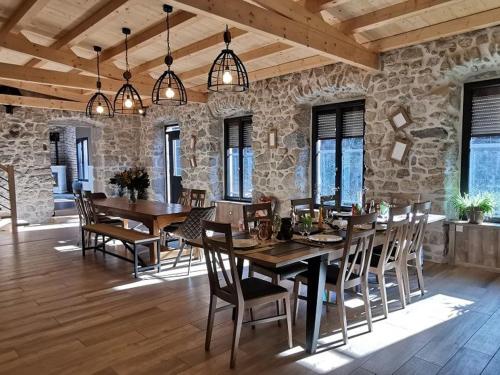 a dining room with wooden tables and chairs and a stone wall at Grand gîte rénové, billard, baby-foot, vue sur rivière, terrasse, activités diverses - FR-1-582-76 in Le Chambon-sur-Lignon
