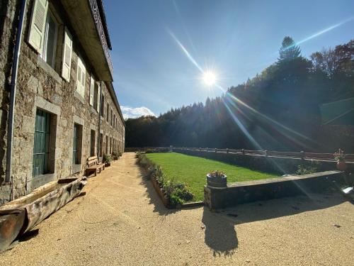 a building with a bench next to a green field at Grand gîte rénové, billard, baby-foot, vue sur rivière, terrasse, activités diverses - FR-1-582-76 in Le Chambon-sur-Lignon