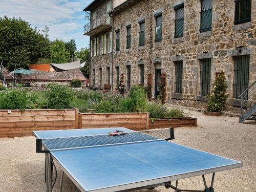 a ping pong table in front of a brick building at Grand gîte rénové, billard, baby-foot, vue sur rivière, terrasse, activités diverses - FR-1-582-76 in Le Chambon-sur-Lignon
