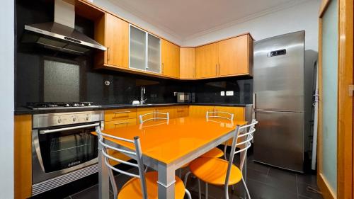 a kitchen with a yellow table and a stainless steel refrigerator at Coastal Comfort at Riverside - 4 Min to Airport! in Santa Cruz