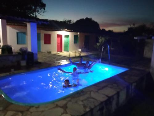 two children playing in a swimming pool at night at Sitio pousada Santo Antônio in Itaporanga dʼAjuda