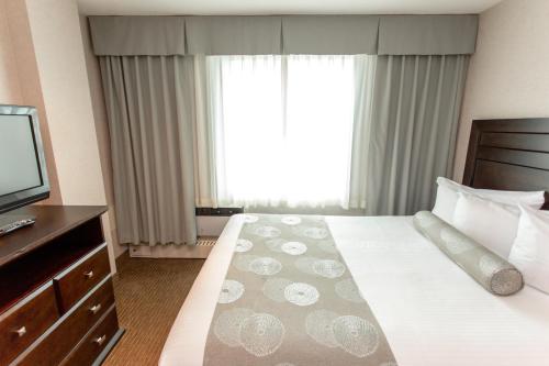 a hotel room with a bed and a television at Campus Tower Suite Hotel in Edmonton