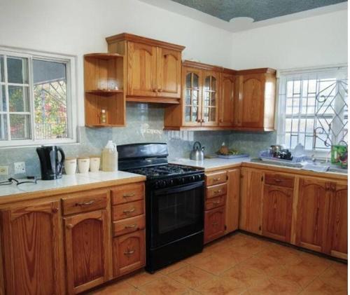 a kitchen with wooden cabinets and a black stove at 6 bedroom KeiraHideaway in Yallahs