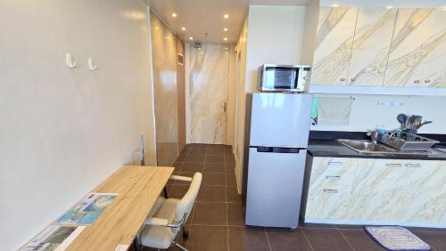 a kitchen with a refrigerator and a table with a microwave at La Mirada Residences in Mactan
