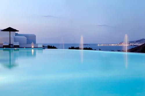 a swimming pool with an umbrella and the water at Hotel Mediterranean in Stelida