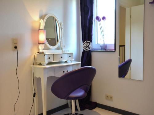 ein Badezimmer mit einem lila Stuhl und einem Spiegel in der Unterkunft Lake-view apartment with sauna, hot tub in Grand Coo