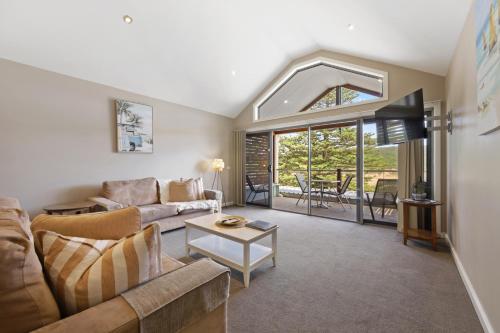 una sala de estar con un sofá y una mesa en Sea Foam Villas, en Port Campbell