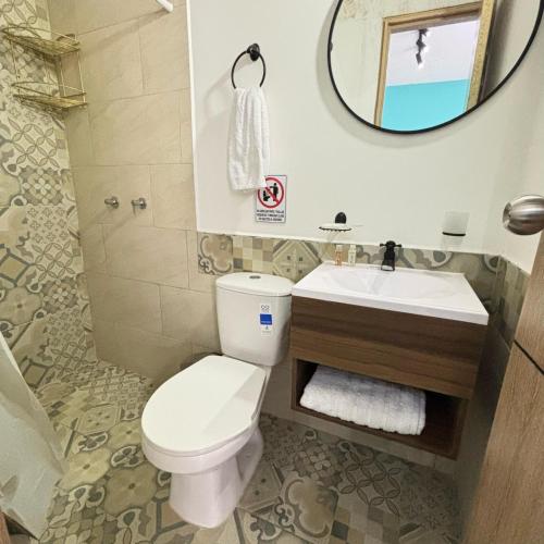 a bathroom with a toilet and a sink and a mirror at HOTEL CASA VECCHIA San Antonio in Cali