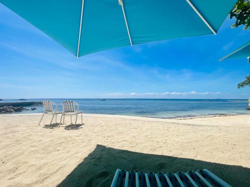 two chairs sitting on the beach under an umbrella at Condo with Private Beach at Tambuli Beach Resort near Airport in Cebu in Lapu Lapu City