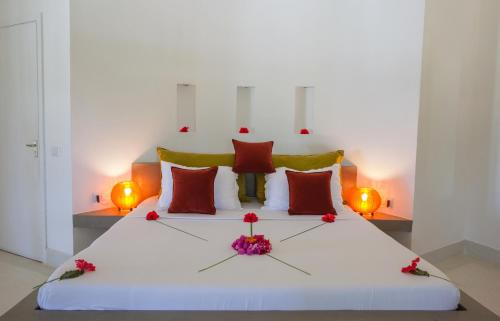 a white bed with red pillows and flowers on it at The Kasa Malindi in Malindi