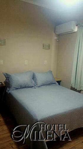 a bed with blue pillows in a room at Hotel Milena in Mendoza