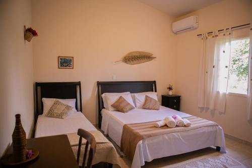 a bedroom with two beds and a table and a window at Pousada e Chalés Passaredo Canastra in São Roque de Minas