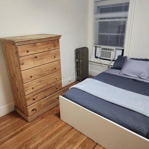 a bedroom with a bed and a wooden dresser at New York City Guest House 2 in New York