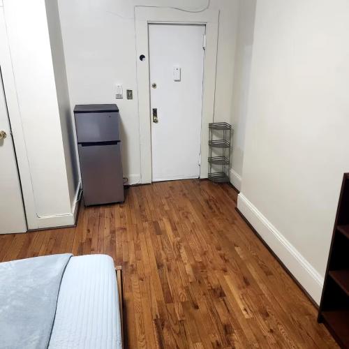 an empty room with a refrigerator and a hard wood floor at New York City Guest House 2 in New York