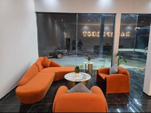 a living room with orange couches and a table at Rainforest Hotel in Paksong