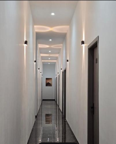 a hallway with white walls and a long hallway with lights at Rainforest Hotel in Paksong