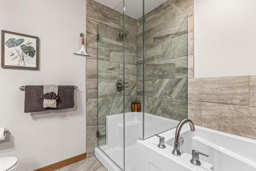 a bathroom with a shower and a tub and a sink at Spring Creek Luxury King One Bedroom at White Spruce Lodge in Canmore