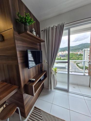 a living room with a tv and a large window at Loft Reis in Joinville