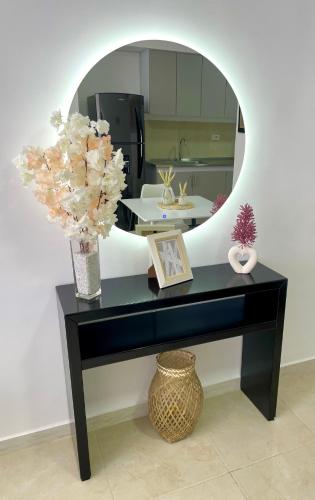 a black table with a mirror and a vase with flowers at Acogedor y elegante Apartamento in Valledupar