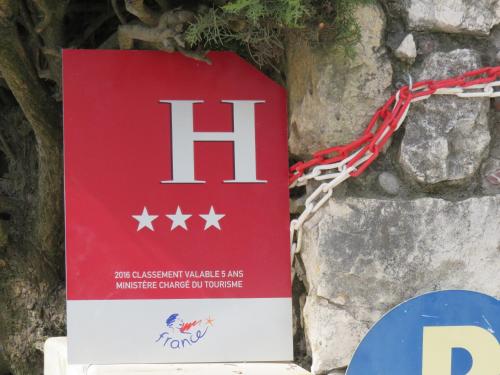a red and white sign hanging on a stone wall at Hotel mon Soleil in La Gaude