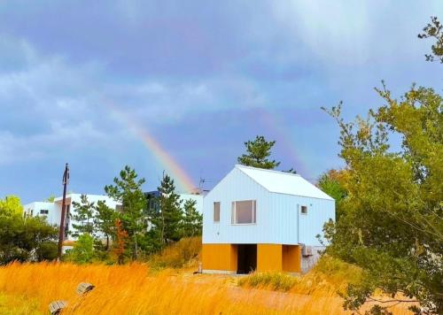 a white house with a rainbow in the background at furaha in Iwamicho