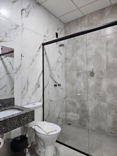 a bathroom with a toilet and a glass shower at Oriente Hotel in Campo Novo do Parecis