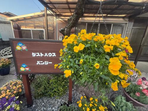 a sign in front of a bunch of flowers at 一棟貸ゲストハウス　パンジー in Nachikatsuura