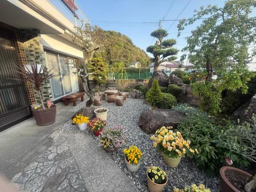 a garden with potted plants and flowers in front of a house at 一棟貸ゲストハウス　パンジー in Nachikatsuura