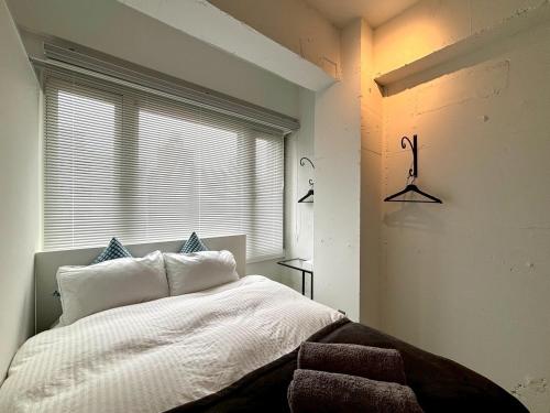 Un dormitorio con una cama blanca y una ventana. en GalleryInn Fuji, Shibuya, en Tokio