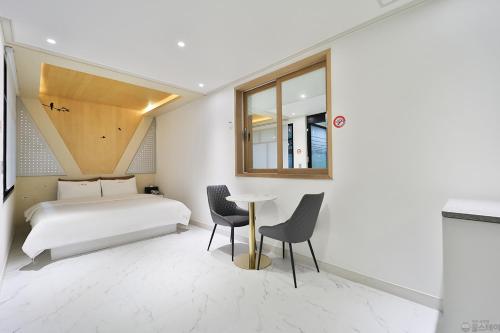 a bedroom with a bed and a table and chairs at Time Hotel in Yangsan