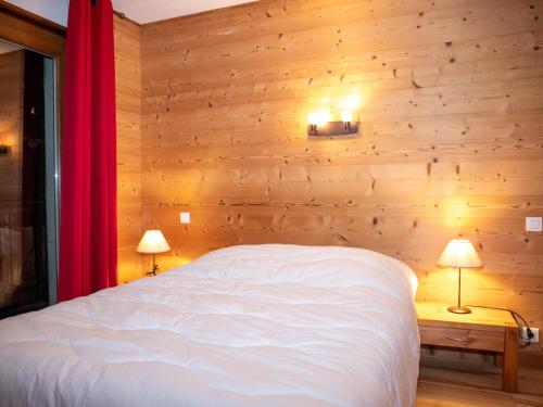 - une chambre dotée d'un mur en bois avec un lit et deux lampes dans l'établissement Appartement 3 chambres aux Gets avec balcon exposé sud, proche pistes et centre - FR-1-671-99, aux Gets