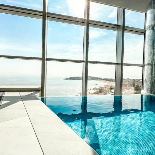 a swimming pool in a building with a view of the ocean at 青岛海天大酒店 山海相拥典雅奢华 in Qingdao