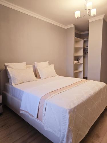 Un dormitorio con una cama grande con sábanas y almohadas blancas. en Алматушечка, en Almaty